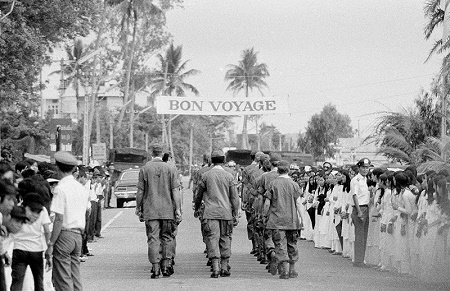 A bon voyage banner stretches overhead in Da Nang, South Vietnam, as soldiers march down a street following a farewell ceremony for some of the last U.S. troops in the country’s northern military region, on March 26, 1973.-AP