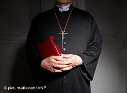 a priest in a church, holding a bible 